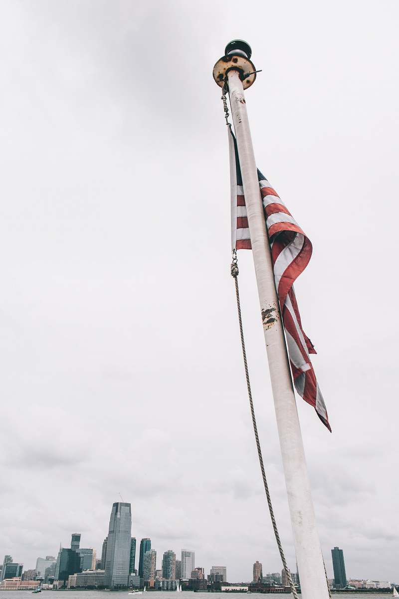 united states flag of US raised on white metal pole tower